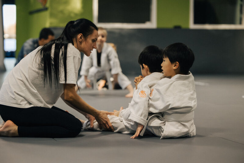 Trainerin mit Kindern auf der Matte bei Grapple Town